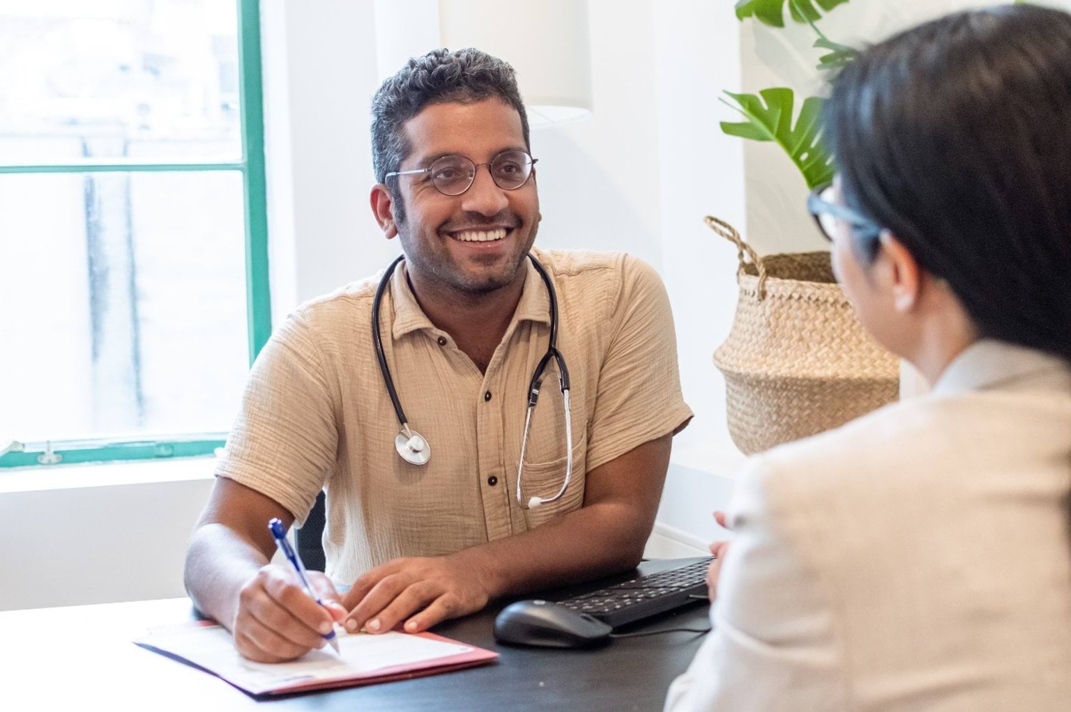 Doctor smiles across a desk to his patient