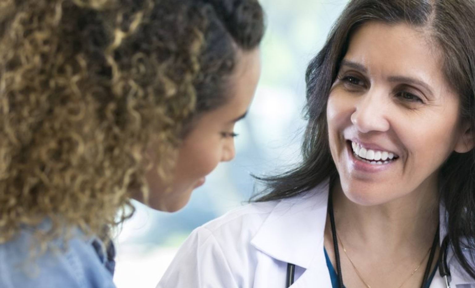 female doctor in white coat talking to another woman