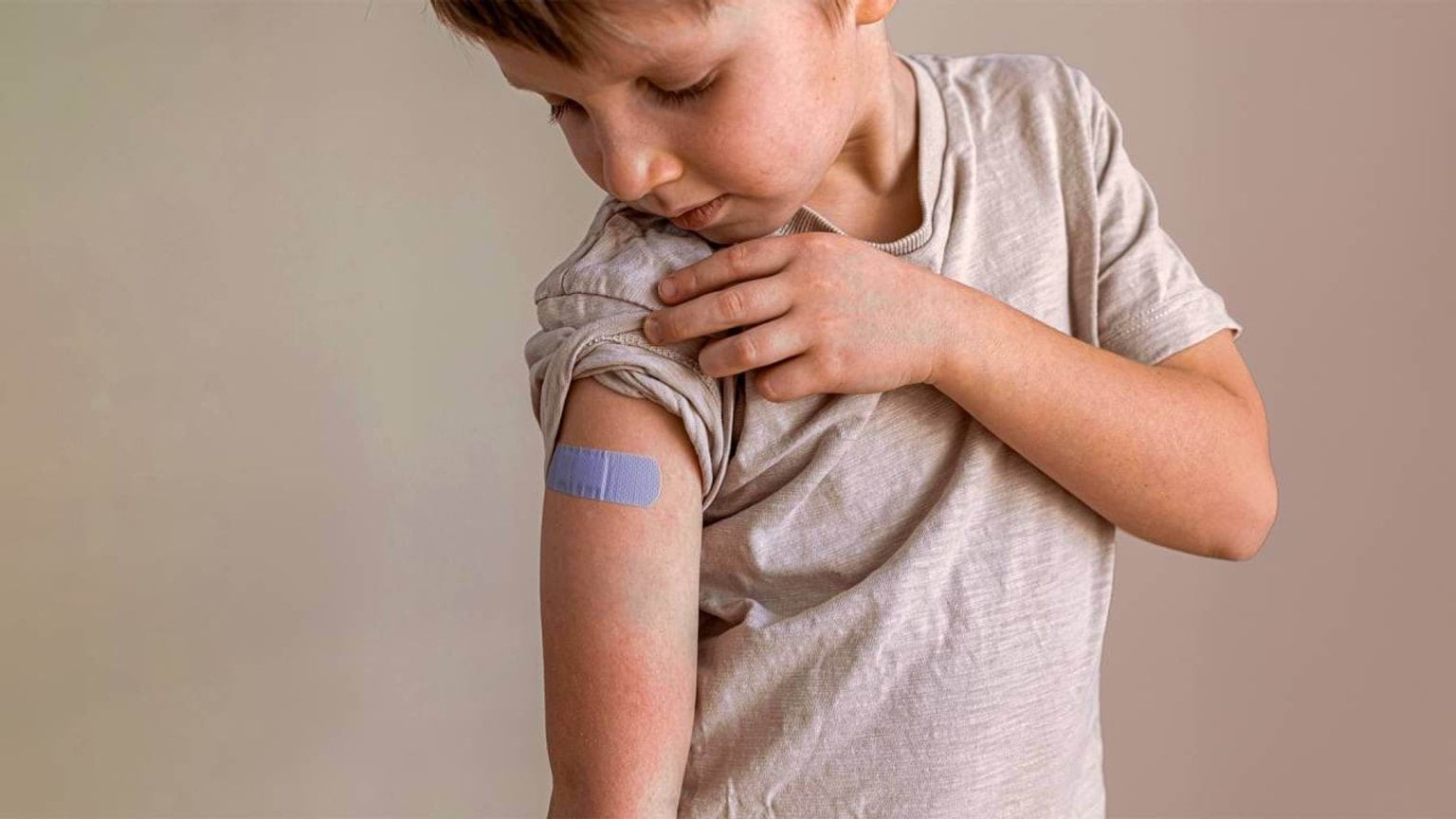 Boy looks at bandaid on arm after vaccination
