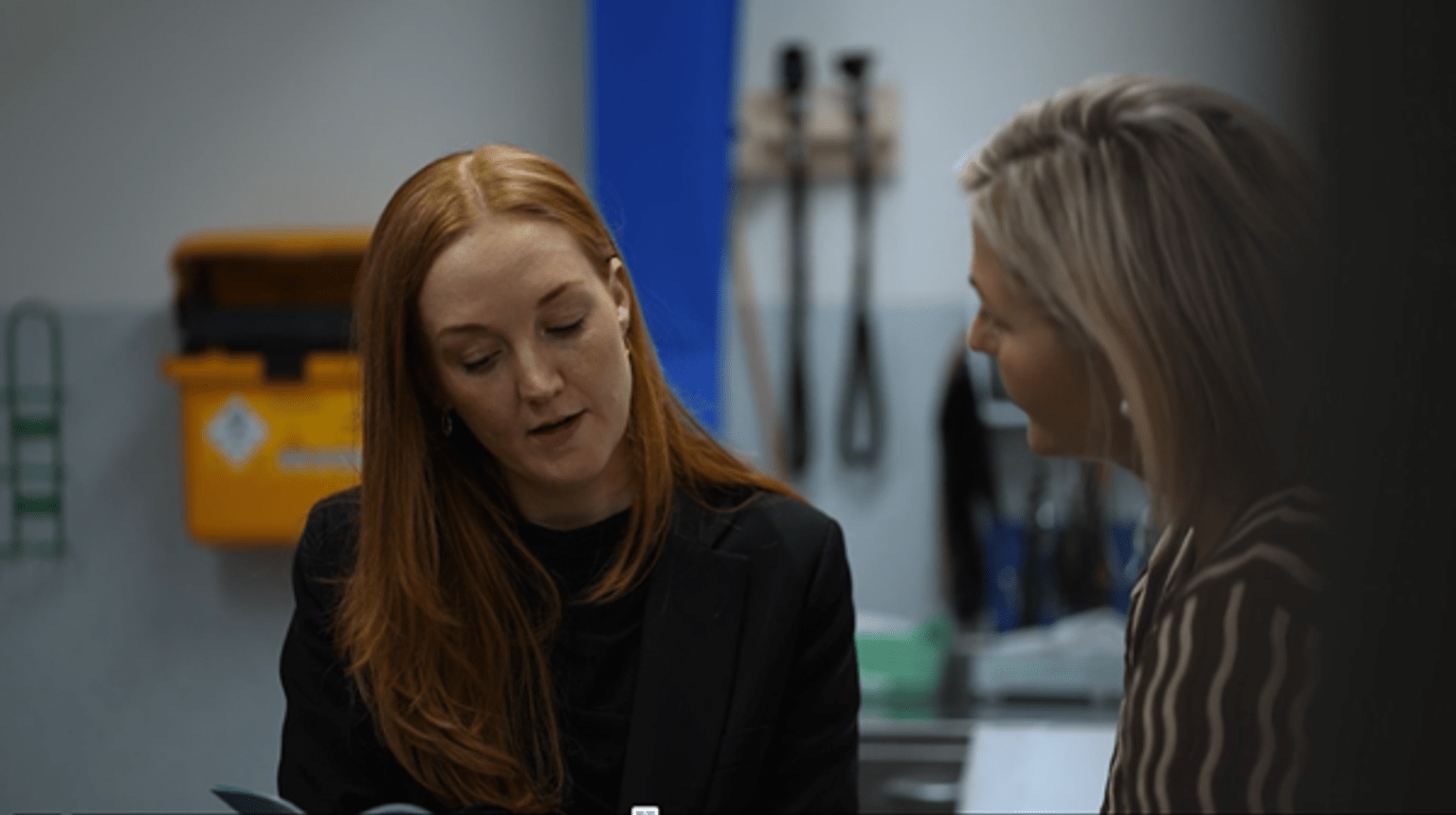 Two women looking at a medical chart and talking to each other.