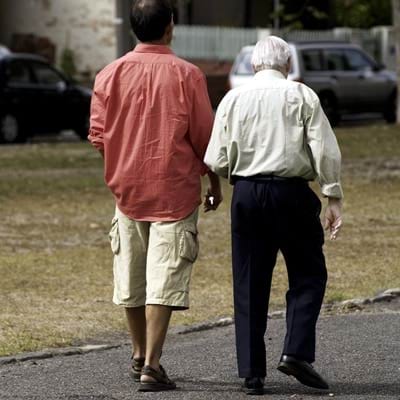 A younger and older man are walking together on a level, safe garden path.